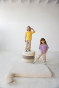 two kids standing on boucle pouf boy bettys home next to boucle mattress 