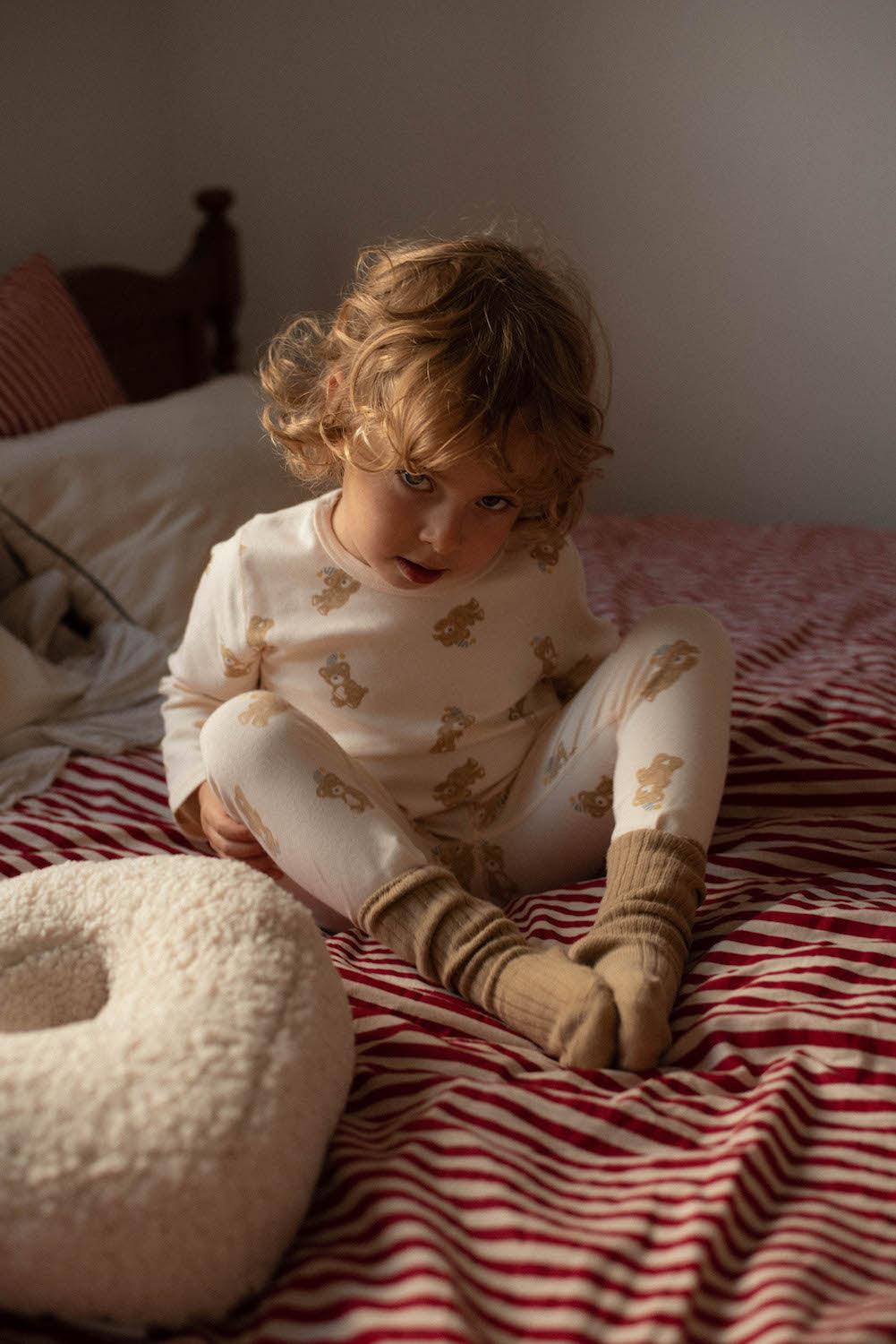 little boy sitting on bed next to boucle pillow y bettys home 