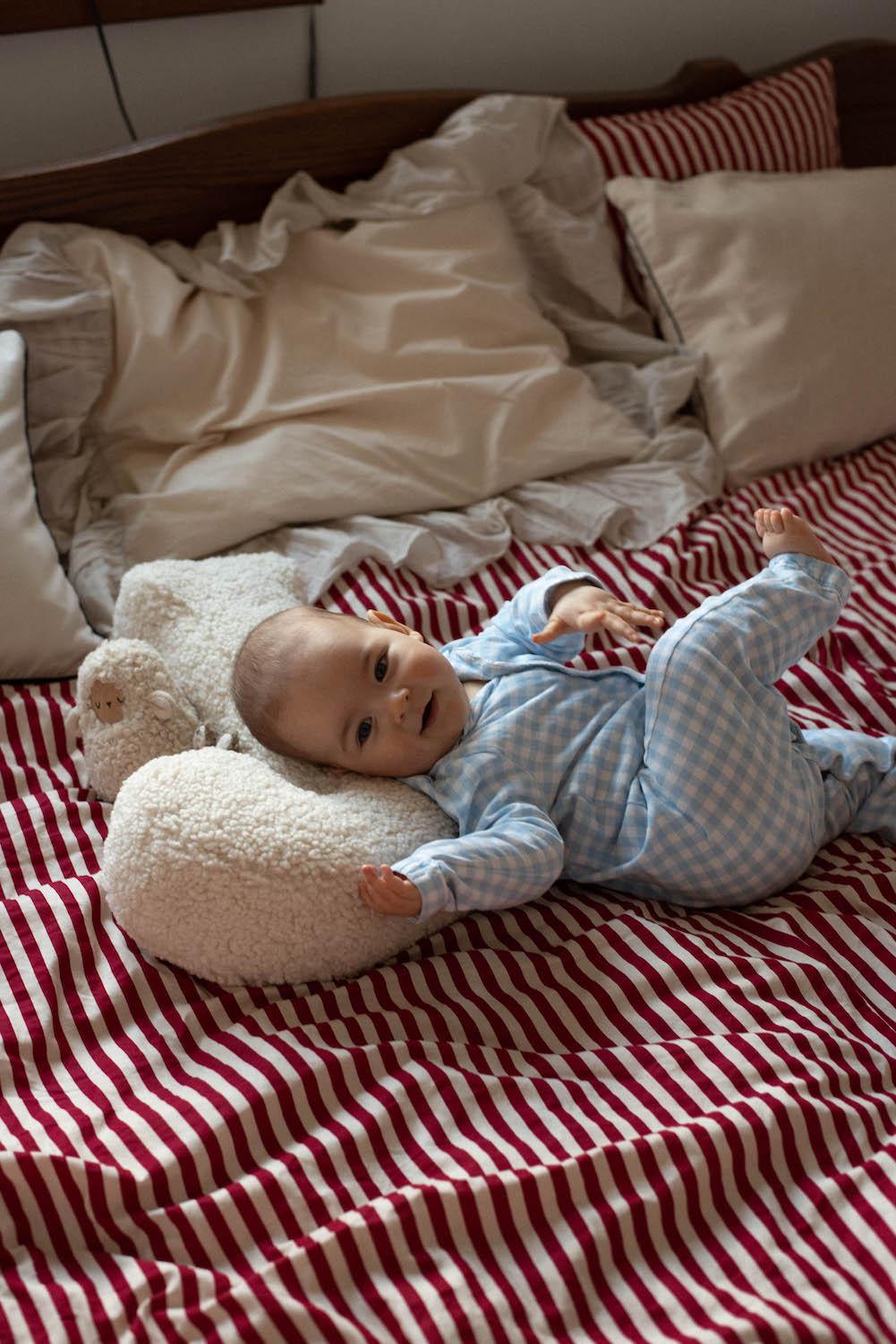 little baby lying on boucle cushion by bettys home in his bed