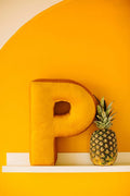 vevet lettere cushion p yellow by bettys home standing on shelf next to pineapple on yellow wall 